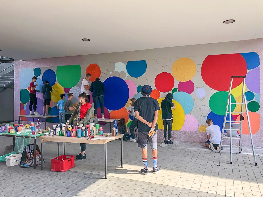 Gruppe gestaltet die Wand mit bunten Kreisen.